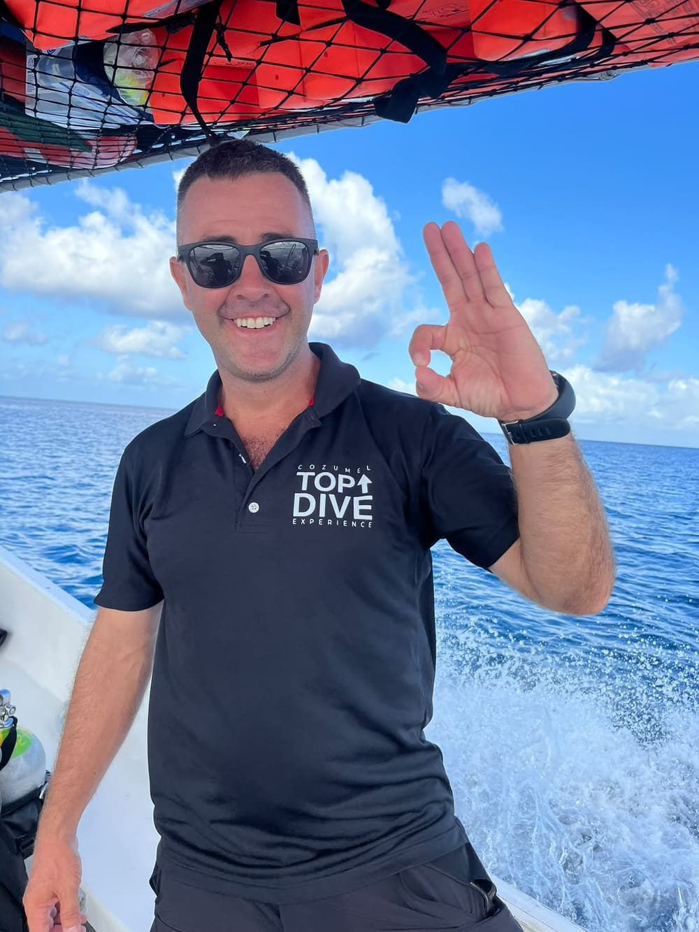 Julen Carrero on the boat in a Cozumel Top Dive Experience shirt, giving the OK sign