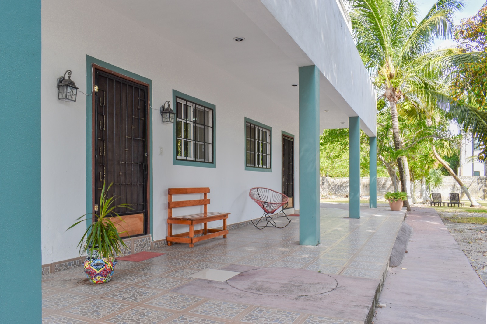 Covered terrace at the Perfect Place apartments with palms and seating